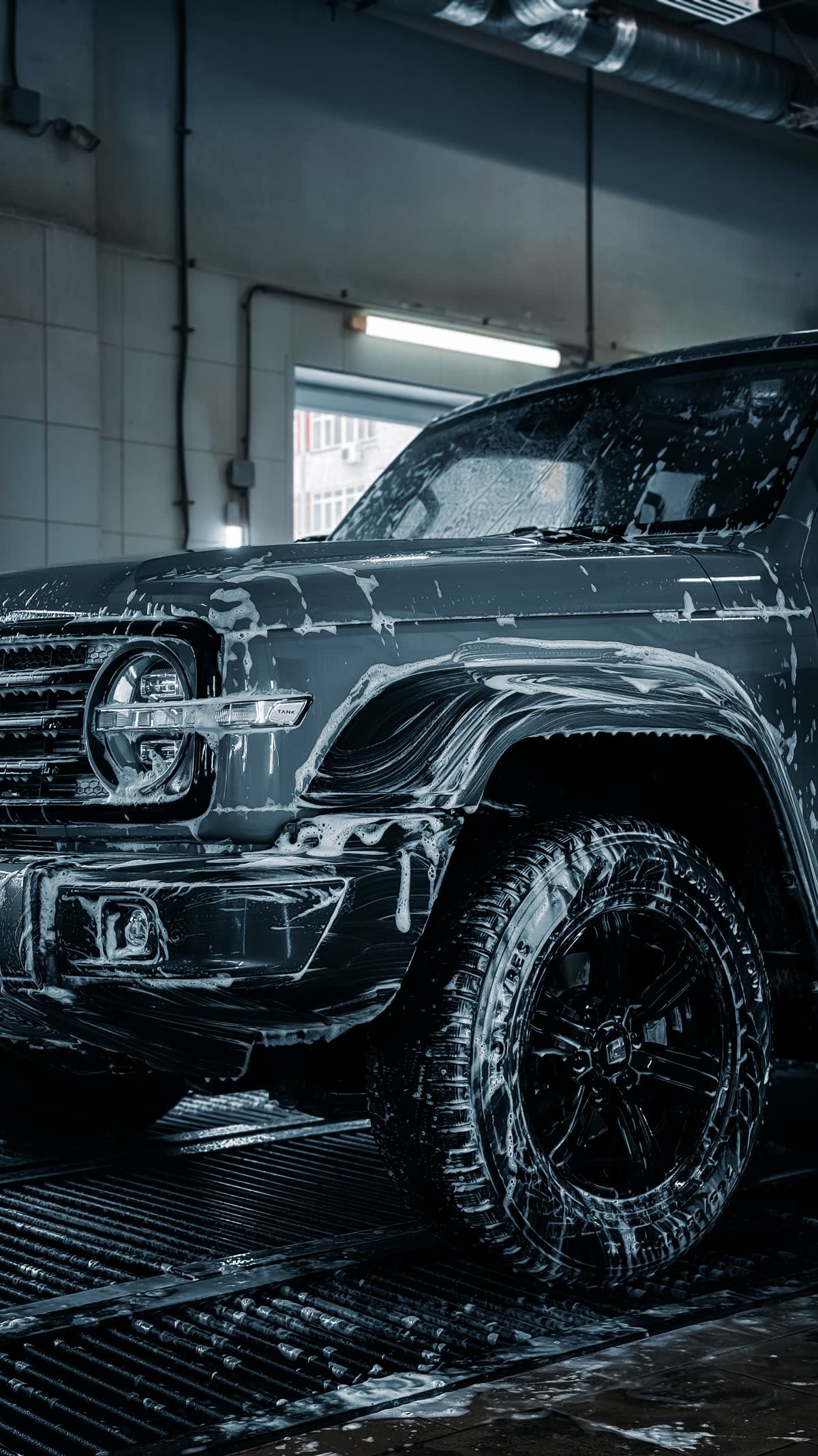 SUV covered in snow foam at the wash bay